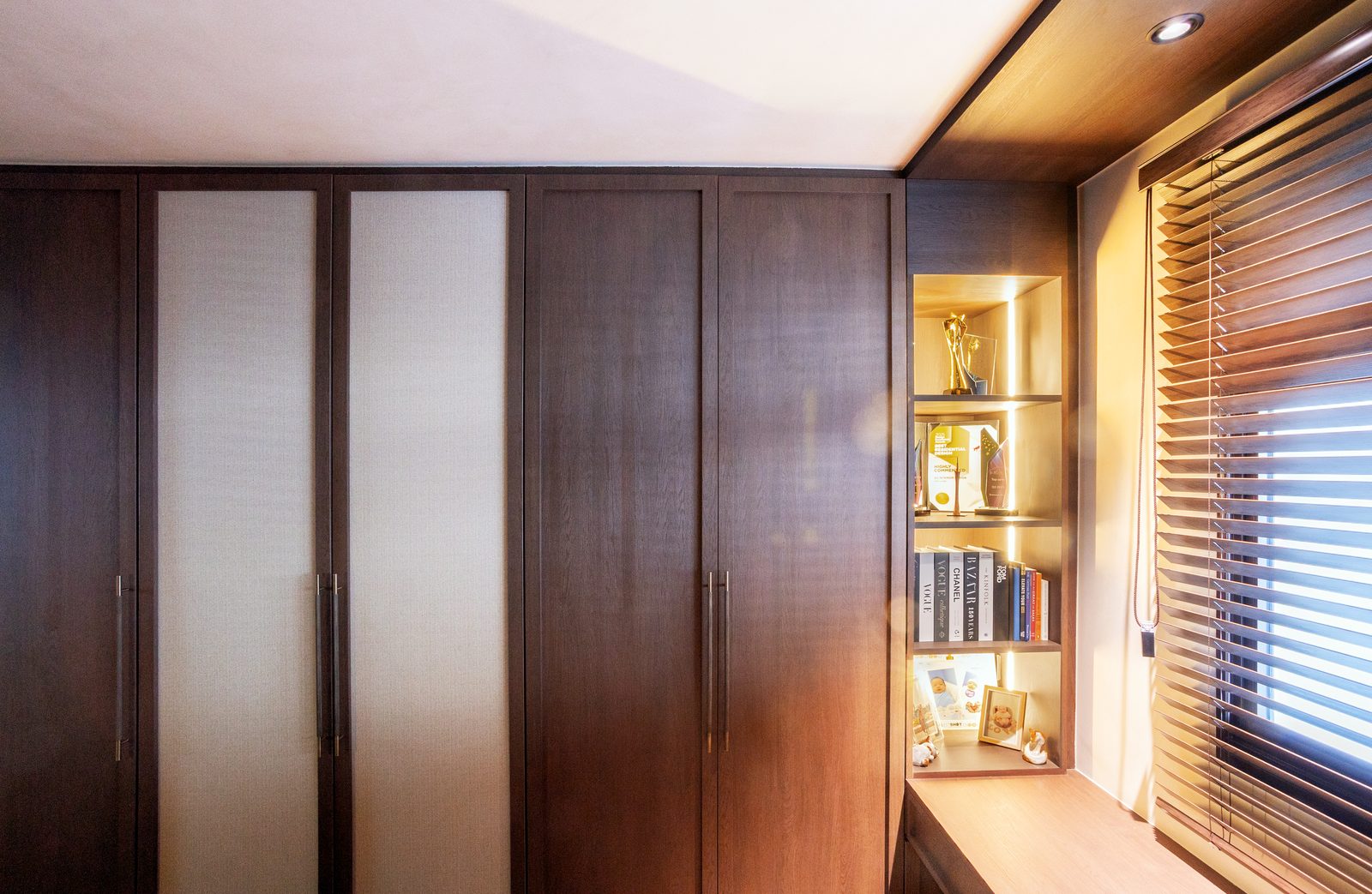 Walk-in wardrobe with illuminated display shelving and dark timber joinery
