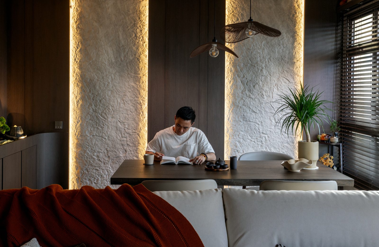 Designer Brennan Phua reading at the dining table in the Japanese-inspired space