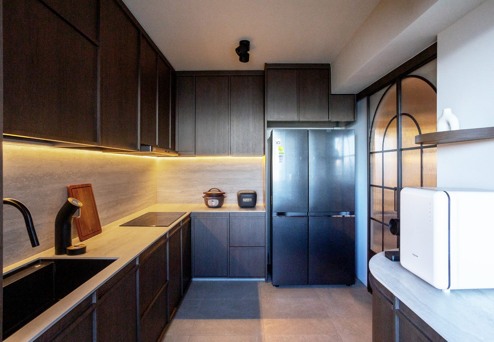 Kitchen with dark timber cabinetry, travertine backsplash, and black appliances